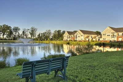 Peaceful retention pond in the center of the community. A bench is in the foreground and Central Park's apartment buildings in the background. 