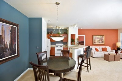 Dining area next to the kitchen. Features a dark, dusty blue accent wall and black dining set with four chairs.