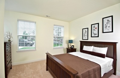 Spacious bedroom and several large windows and tasteful wall decor.