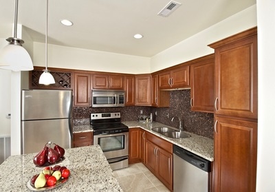Spacious kitchen with medium stained wood cabinets, granite countertops, an island, and stainless steel appliances.