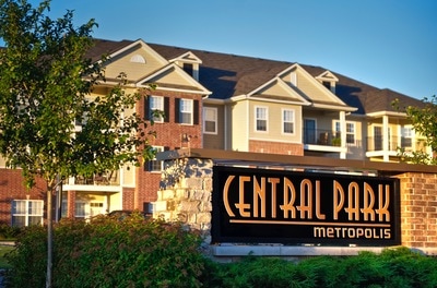 Central Park's entrance sign with apartment buildings in the background.