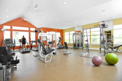 Fitness center with equipment, yoga balls, and weights. Large windows surround all sides.